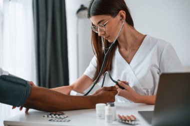 Sağlık sigortası gebeliği. Kadın doktor bir erkeğin kan basıncını ölçer..