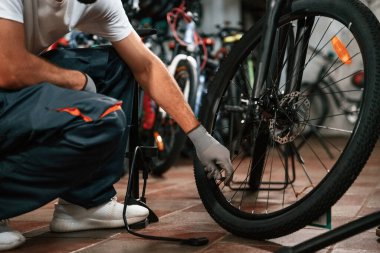 Lastiği el pompasıyla şişiriyor. Bisikleti tamir eden adamın ellerine yakından bakın..