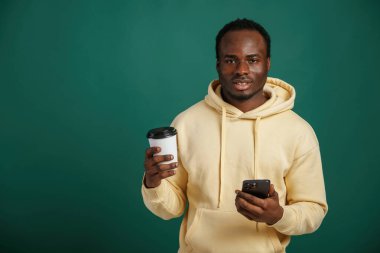 Kahve fincanı elimde. Afrikalı Amerikalı adam stüdyoda yeşil arka plana karşı duruyor..
