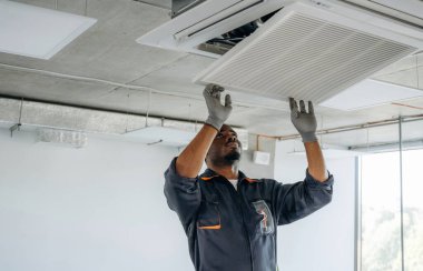 Havalandırmayı tamir ediyorum. Tamirci modern ofiste kapalı bir yerde..