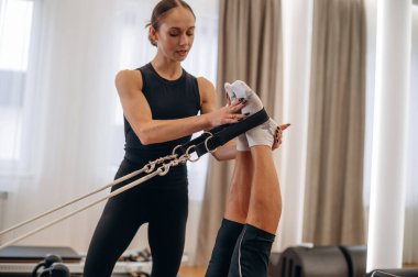 Uzanmak ve bacak egzersizi yapmak. Kadın eğitmen yaşlı kadına yardım ediyor..