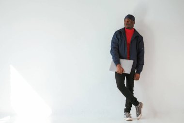 Dizüstü bilgisayarı elimde tutuyorum. Stüdyoda beyaz arka plana karşı siyah adam var..