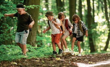 Patikaya doğru gidiyor. Çocuklar yazın gündüz vakti ormanda..
