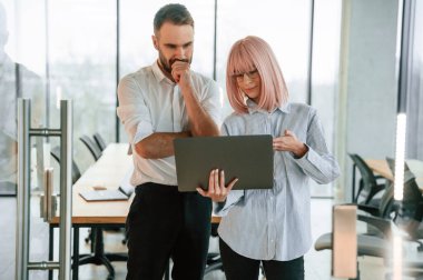 Laptop kullanıyorum. Kadın ve erkek ofiste birlikte çalışıyorlar..