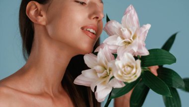 Nilüfer çiçeğini tutarken yumuşak bir his. Genç kadın stüdyoda arka planda..