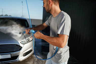 Otomobil yıkama, adam dışarıda arabasıyla bekliyor..