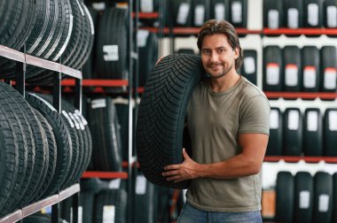 Lastiği müşteri seçiyor. Lastik tamir servisinde adam var..