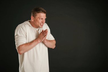 Kirli düşünceler, ellerini ovuşturuyor. Adam stüdyoda arka plana karşı..