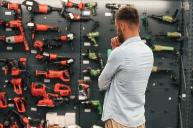 Yepyeni matkaplarla dolu bir duvar. Adam hırdavatçıda..