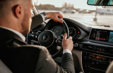 Direksiyona yakından bak. Siyah takım elbiseli adam arabada oturuyor..