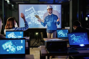 Bir şeyleri açıklamak. Erkek mimar, insanlar için mavi projektör üzerinde inşaat alanı projesi gösteriyor.