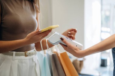 İşçi terminali tutuyor. Perakende mağazasında kadın kıyafetlerin parasını ödüyor..