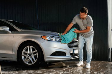 Yandan bak, otomobili parlatmak için bez kullan. Adam dışarıda arabasıyla bekliyor..