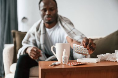 Masanın üzerinde duran haplar. Hasta siyah adam evde..