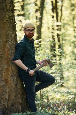 Oduncu ayakta duruyor. Sakallı adam gündüz vakti ormandadır..