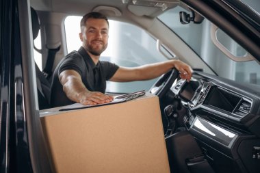 Teslimatçı ya da yükleyici kutuyla birlikte arabada..