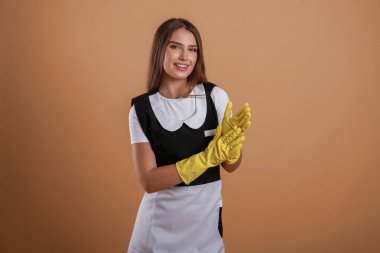 Bitti, iş bitti, oda hizmetçisi sarı eldivenli. Genç ve güzel bir bayan stüdyoda arka plana karşı..