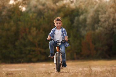 Ata binmek, eğlenmek. Tatlı çocuk bisikletiyle sahada..