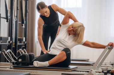 Sırt egzersizi. Kadın eğitmen yaşlı kadına yardım ediyor..