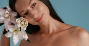 Zambak çiçekleriyle poz vermek. Genç kadın stüdyoda arka planda..