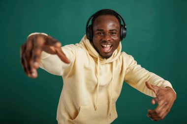 Müzik dinlemek, dans etmek. Afrikalı Amerikalı adam stüdyoda yeşil arka plana karşı duruyor..