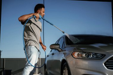 Yüksek basınç, otomobili yıkamak. Adam dışarıda arabasıyla bekliyor..