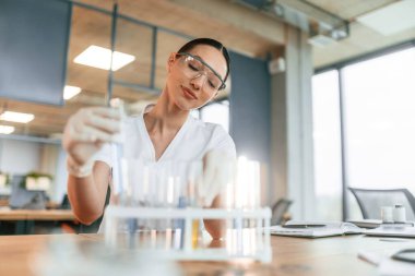 Bir sürü test tüpüyle çalışıyorum. Beyaz önlüklü kadın doktor içeride..