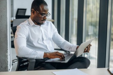 Dizüstü bilgisayarla. İşadamı modern ofiste çalışıyor..