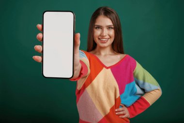 Beyaz akıllı telefon ekranı, mesaj için yer. Genç bir kadın stüdyoda yeşil arka plana karşı duruyor..