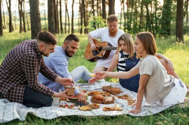 Boş zaman kavramı, sağlık. Bir grup arkadaş, ekolojik kutularda yiyeceklerle sahada piknik yapıyorlar..