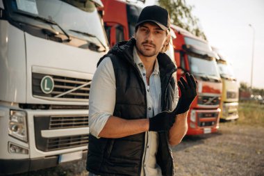 Siyah eldiven giyiyor. Kamyon şoförü açık havada nakliye aracının yanında..