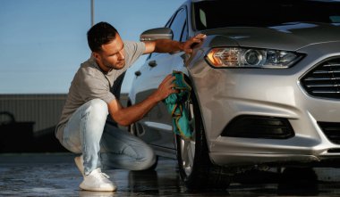 Araba yıkama, cilalama işi. Adam dışarıda otomobille geziyor..