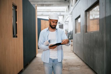 Bitmemiş proje, elinde dijital tablet var. Ahşap depoda sanayi işçisi..