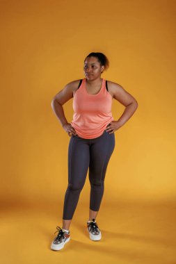Spor kıyafetleri içinde. Afrikalı Amerikalı kadın sarı arka planda stüdyoda..