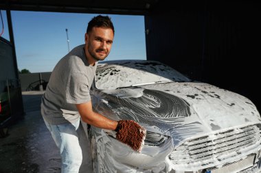 Beyaz sabun ve köpük, otomobili yıkamak. Adam dışarıda arabasıyla bekliyor..