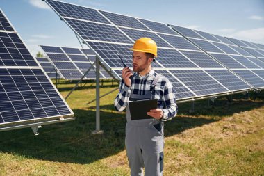 Emirleri telsizle veriyor. Gündüz vakti fotovoltaik güneş panelleri olan bir mühendis..