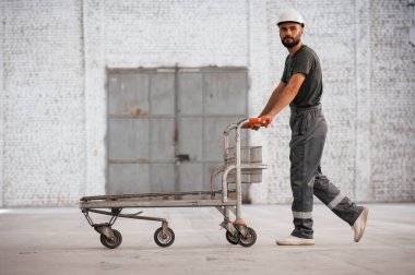 Üzerinde hiçbir şey olmayan palet. Erkek işçi boş depoda..