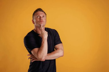 Akıllı, düşünen ve yukarı bakan. Adam stüdyoda arka plana karşı..