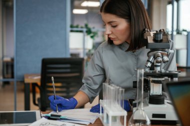 Mikroskopla laboratuvarda. Paltolu kadın doktor içeride..