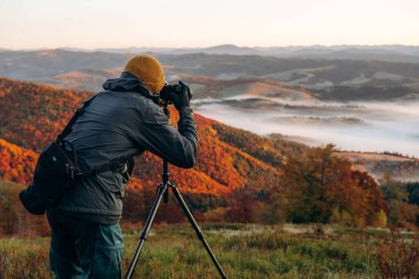 Profesyonel fotoğrafçı tripodun üzerinde kamerayla Karpat dağlarının görkemli manzarasını çekiyor..