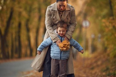 Eğlenceli zamanlardı, oğlanın arkasında. Anne ve oğlu sonbahar ormanlarında yürüyüş yapıyorlar..