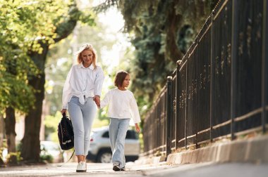 Ön manzara, yürüyüş. Annesiyle okul kızı dışarıda beraberler..
