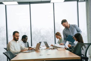 Masada bir sürü dizüstü bilgisayar var. Ofis çalışanlarından oluşan ekip içeride bir arada..