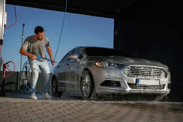 Etrafta dolaşmak ve otomobili yıkamak. Adam dışarıda arabasıyla bekliyor..