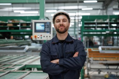 Makineye karşı. Fabrika işçisi kasketli bir şekilde içeride..