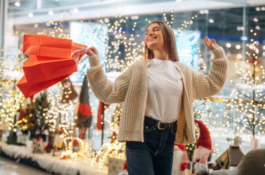 Neşe ve mutluluk. Yeni yıl alışverişi ve hediyeleri. Kadın Noel ağacının yanında..