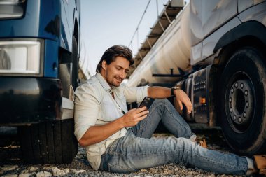 Yerde oturuyordum. Kamyon şoförü açık havada nakliye aracının yanında..