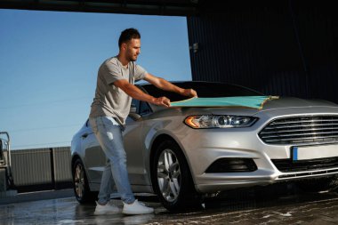 Kumaş, otomobili temizlemek. Adam dışarıda arabasıyla bekliyor..