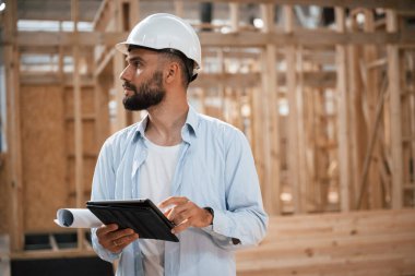 Dijital tablet kontrol altında. Ahşap depoda sanayi işçisi..