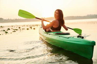 Arkadan bak. Genç kadın gölde yemek masasında..